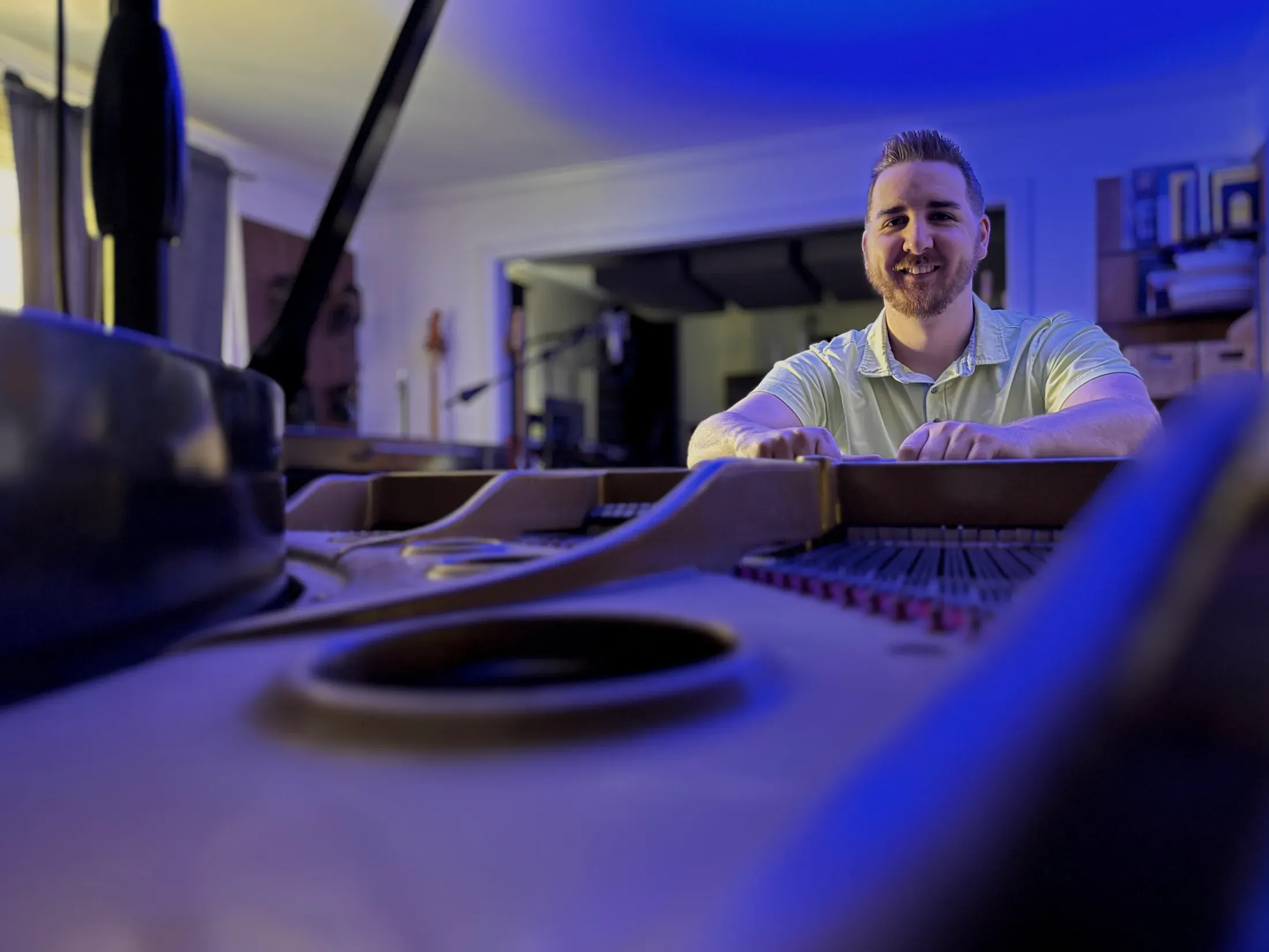 Pierce O’Brien seated behind the strings of a grand piano
